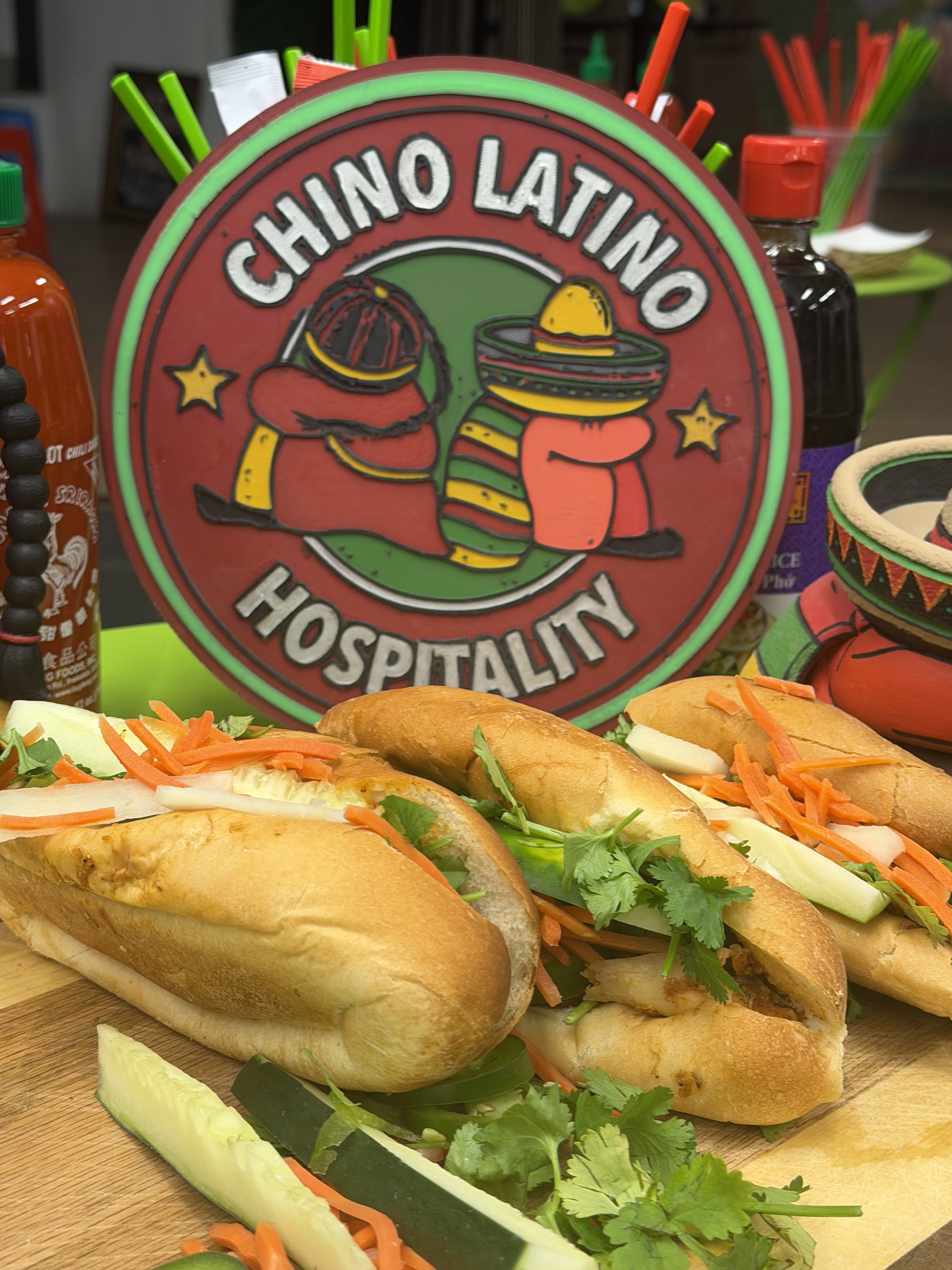 Bánh mì sandwiches with cucumber, carrot, and cilantro in front of the Chino Latino sign